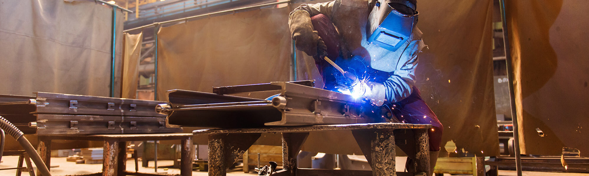 Young man with protective mask welding in a factory